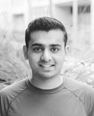 Shrav Mehta in a grey T-shirt, smiling, with trees blurred behind him